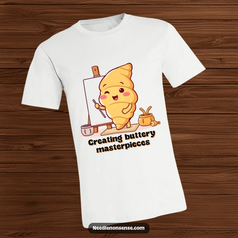 Funny t-shirt with a happy croissant character setting up a canvas, promoting artistic endeavors with a baked goods twist.